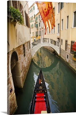 Gondola in  the canal above a  Venetian flag