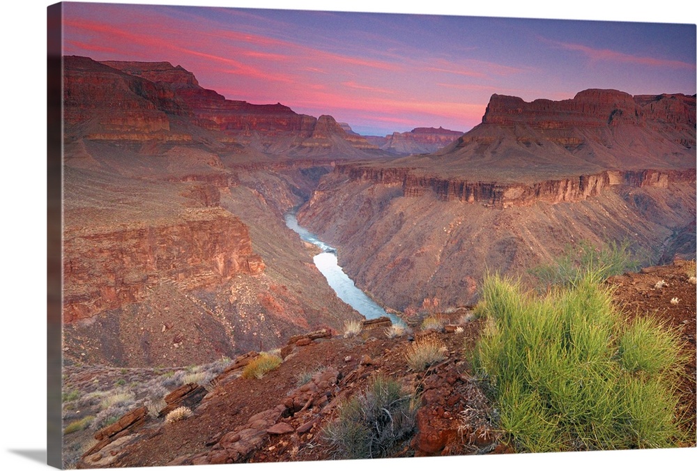 The sun rises on the red rocks of the Grand Canyon as the Colorado River roars down below.
