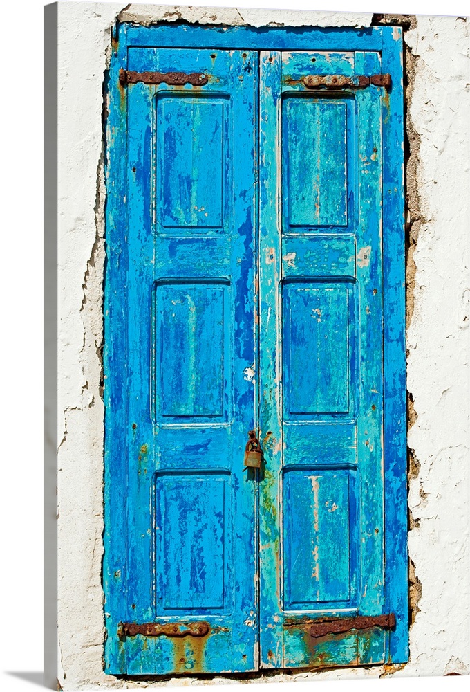 Rustic, paint peeling blue door in the middle of the white side of a home.