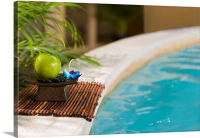 Green apple with massage stones by the pool's edge