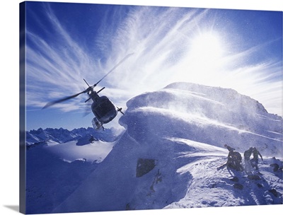 Group of  skiers on mountain top with helicopter