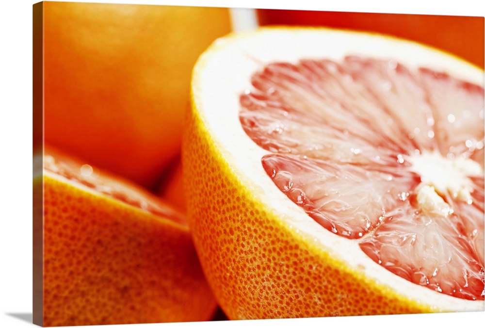 Big, landscape, close up photograph of a grapefruit, sliced perfectly in half, the other half and some whole grapefruits i...