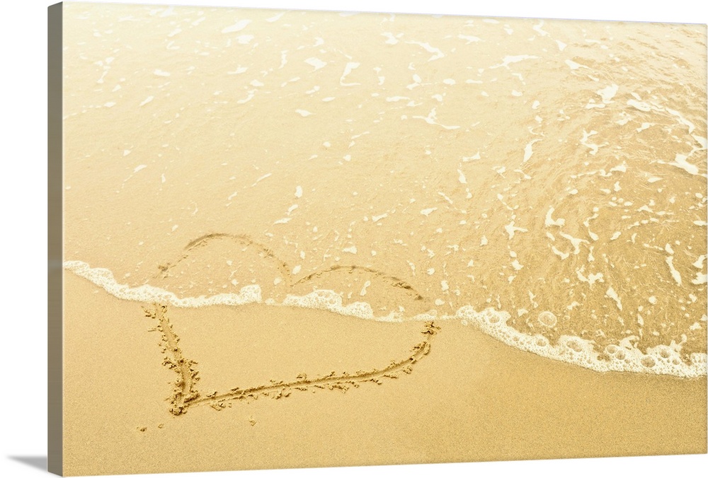 Heart in sand washed away by waves