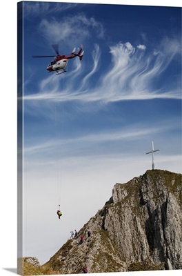helicopter rescue on a mountain side with a cross on the top of the mountain