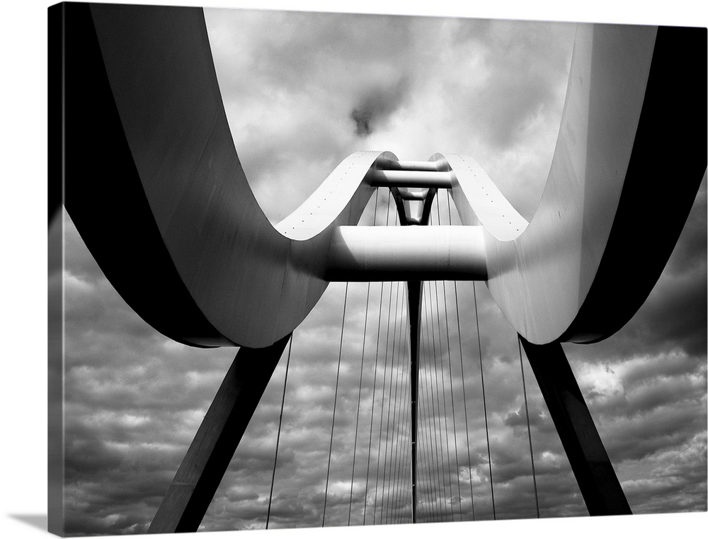 A black and white photograph taken from below the infinity bridge in the UK and looking up to the top of it.