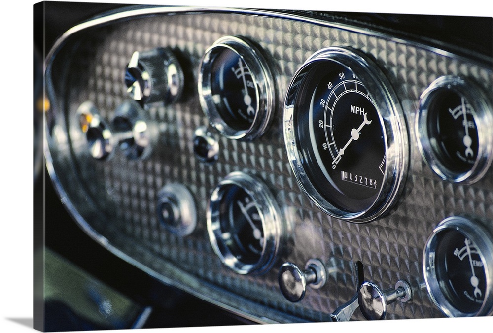 Horizontal, close up photograph on a big canvas of a chrome and black, rounded instrument panel on an antique car.