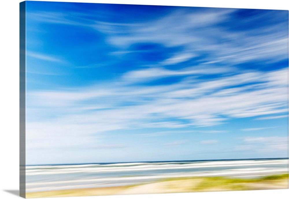 Intentional camera movement of ocean scene of with bright blue sky and wispy clouds. Teewah Beach, Queensland, Australia.