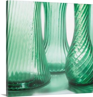 intricately designed glass vases stand together on a reflective surface