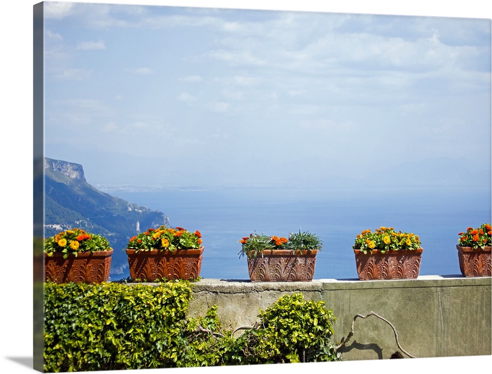 Landscape, large photograph of numerous, rectangle flower pots with flowers, sitting on stone wall overlooking a hazy sky ...