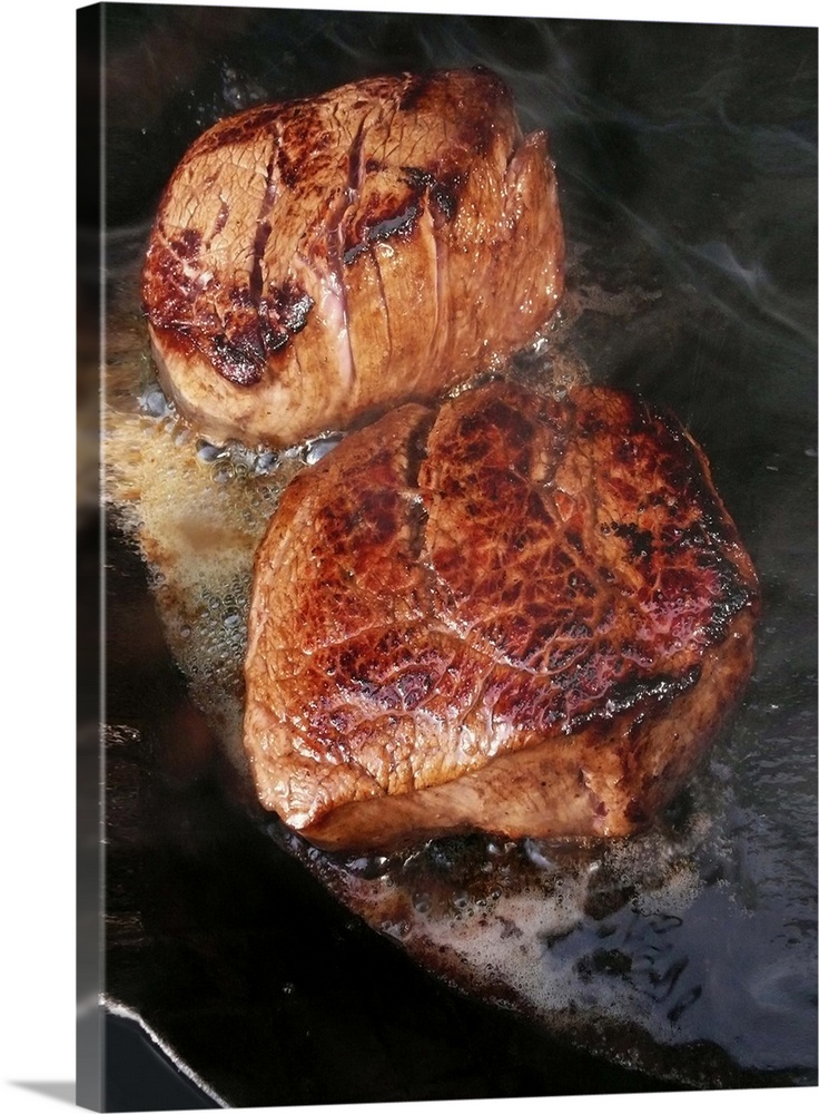 Fillet steaks sizzling in frying pan, close-up