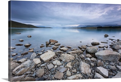 Lake Tekapo in New Zealand, with rocks in foreground during morning cloud.