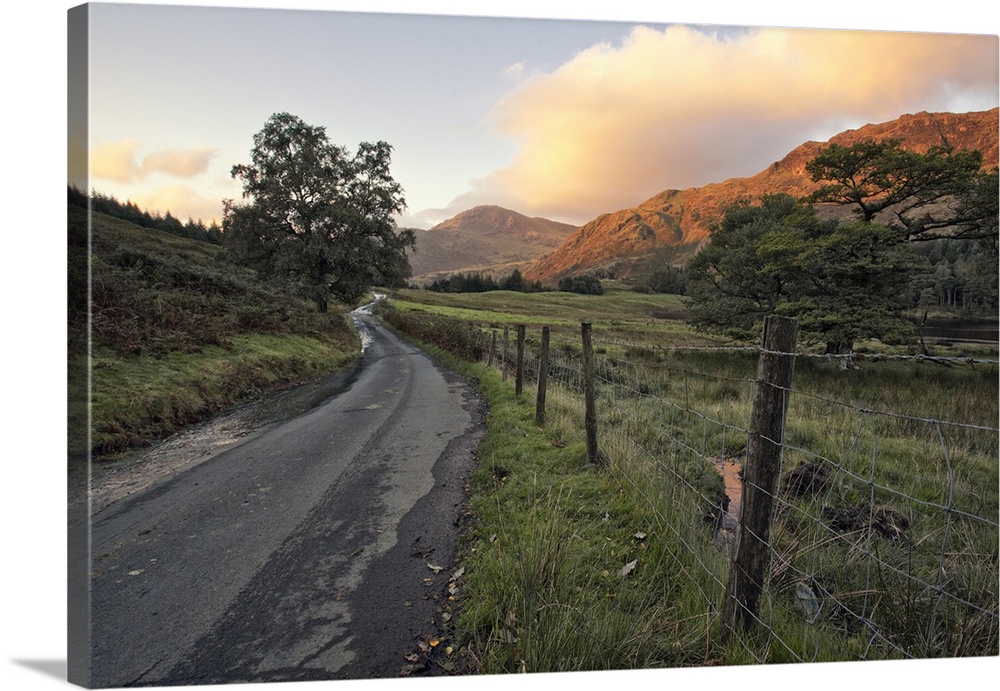 A thin wire fence and winding narrow country road take us through this beautiful Lake District sunrise scene. The dawn pro...