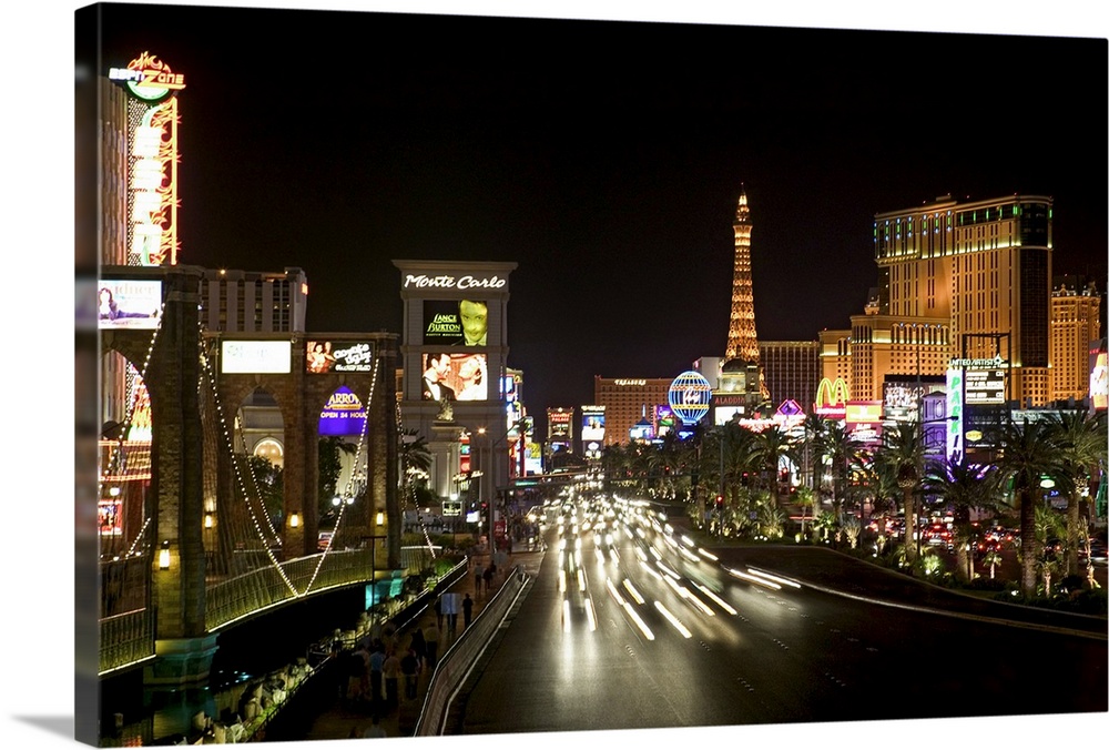 Photograph of "Sin City" after sunset with buildings lit up in the dark sky.  A highway lined with buildings is filled wit...