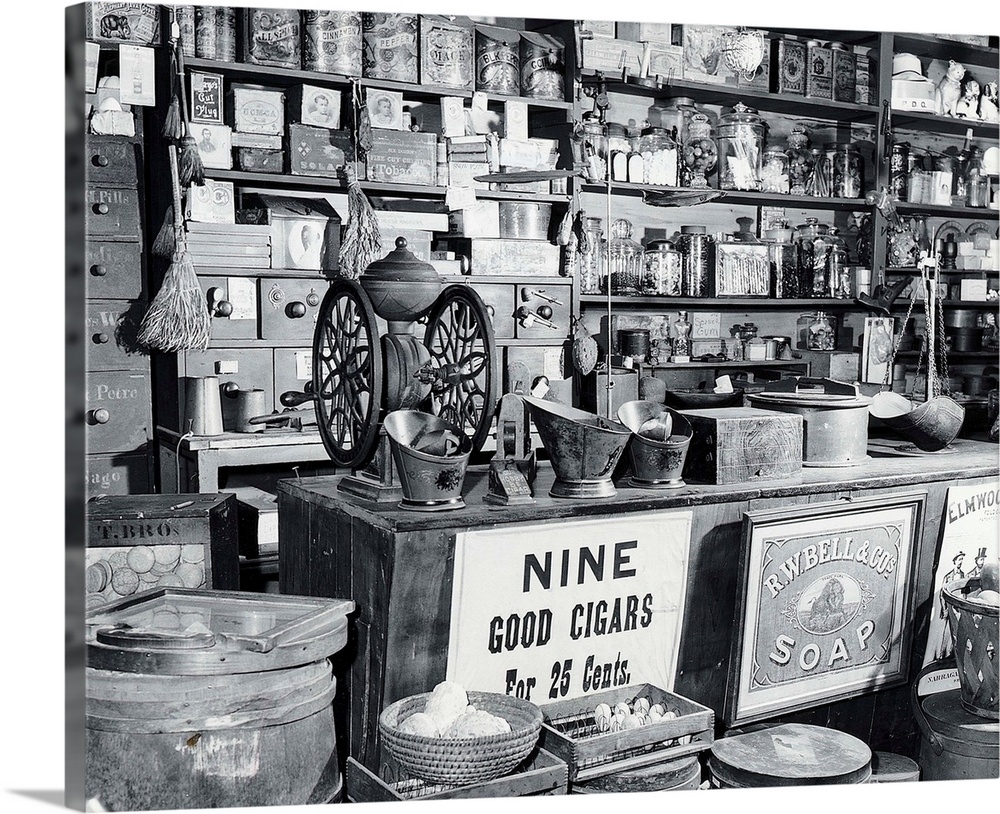 A counter in a general store. Some itemss shown in the photo include: a coffe grinder, spice tins, eggs, candy and a scale...
