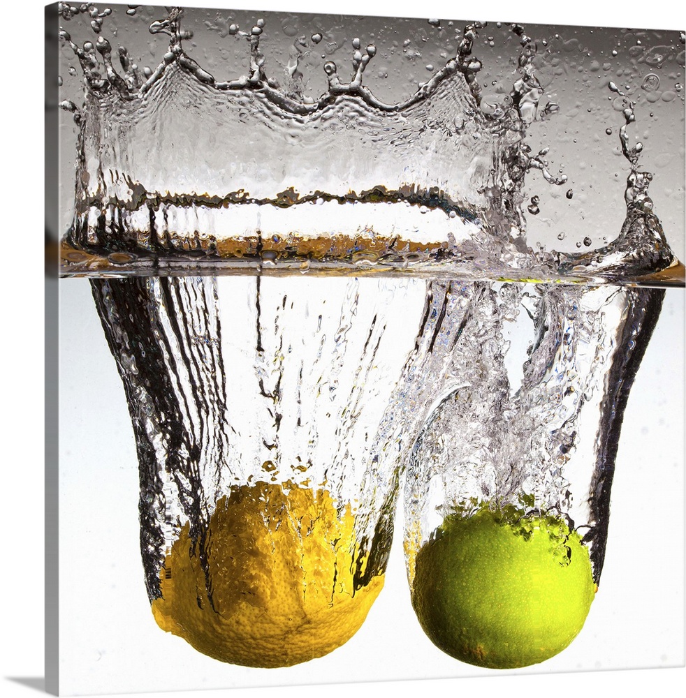 Square canvas photo of a lime and lemon moving through water with water splashing up at the top.