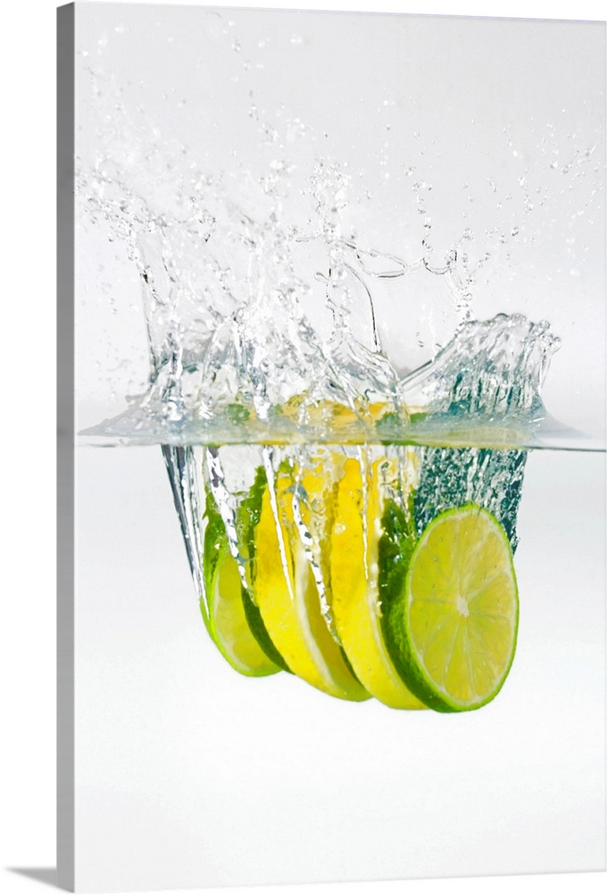 Huge photograph displays four slices of fruit as they splash into water.