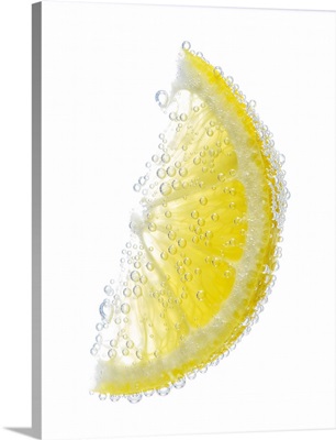Lemon wedge fruit submerged in  water and covered in bubbles