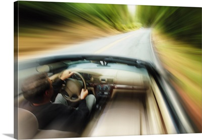 lifestyle photograph of a caucasian man driving fast down a road in a convertible