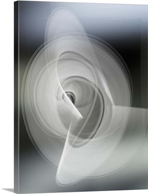 Light trails creating an abstract white swirling circle pattern on a gray background