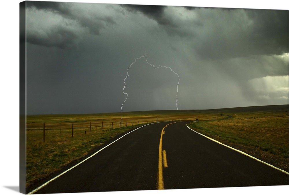 Long and winding road against lighting strike in sky in Santa Fe Trail, Watrous, New Mexico.