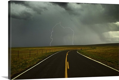 Long and winding road against lighting strike in sky in Santa Fe Trail, New Mexico.