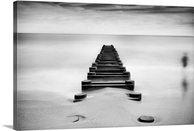 Long exposure black and white image of pipeline extending into ocean.