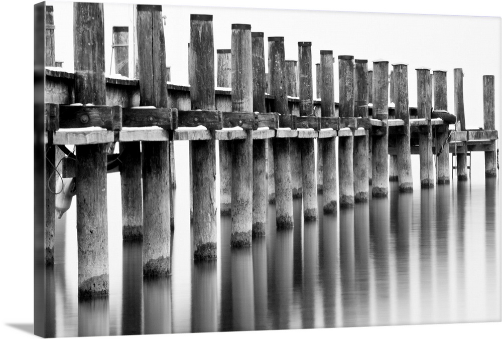 Long-exposure image of pier with reflection in calm water at lake Chiemsee in Bavaria, Germany.