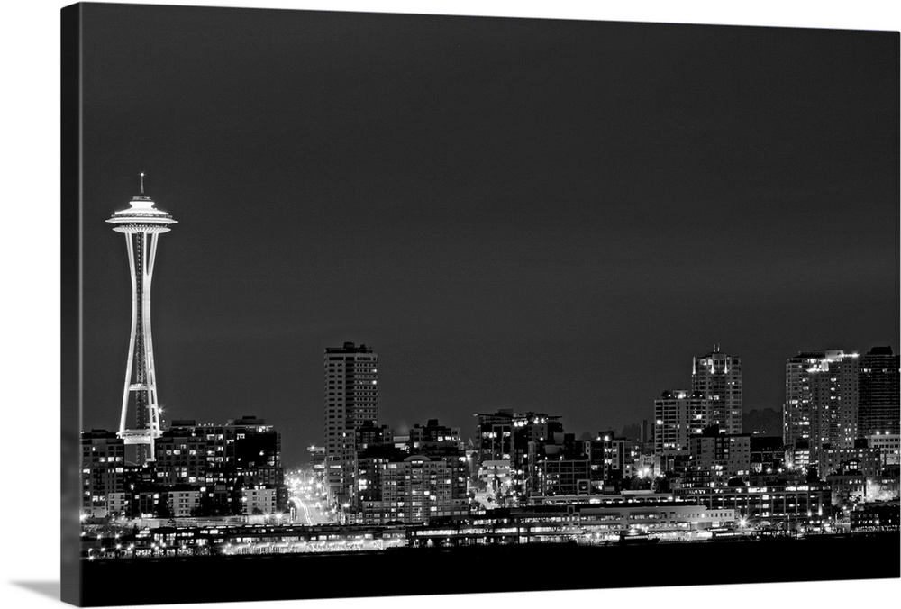 Black and white photograph taken of the city skyline in Seattle with the city illuminated under a night sky.