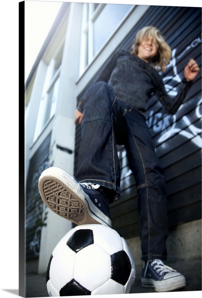 Low angle portrait view  of blond boy with football.