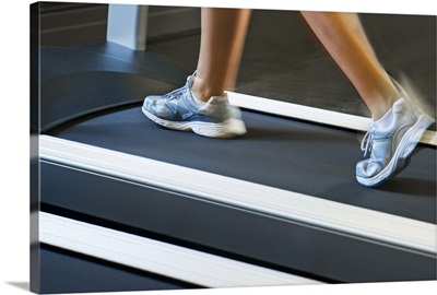 Low section of woman walking on treadmill