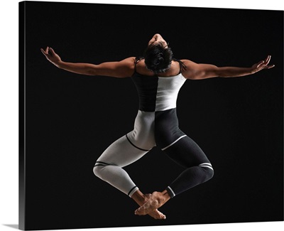 Male ballet dancer in mid air pose, arms extended, rear view