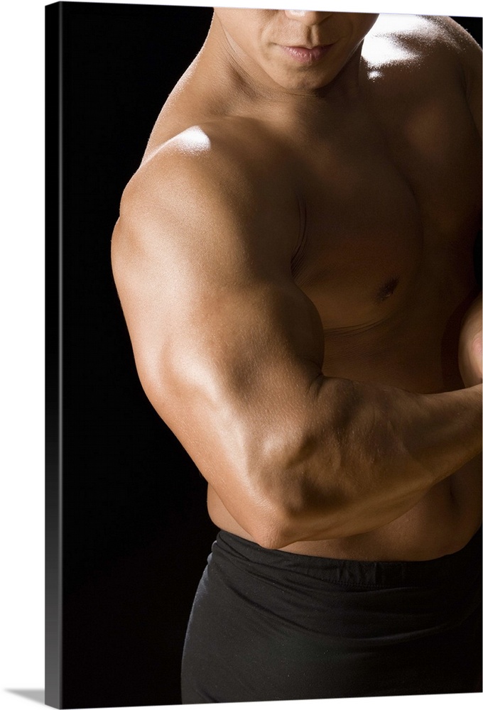 Male bodybuilder flexing muscles, front view, black background