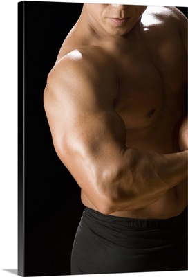 Male bodybuilder flexing muscles, front view, black background