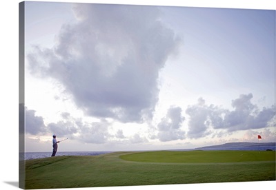 Man at golf course holding golf club, looking away