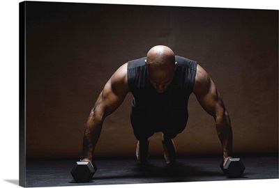 Man doing push-ups on dumbbells, studio shot