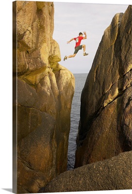 Man leaping over rocky crevice