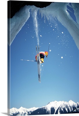 Man skiing, jumping ice off ice cliff, rear view, low angle