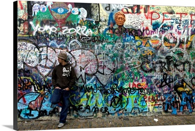 Man standing in front of graffiti, John Lennon Wall.