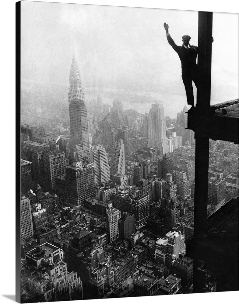 Far above downtown Manhattan, a man holds onto a girder and waves from the construction site of the Empire State Building....