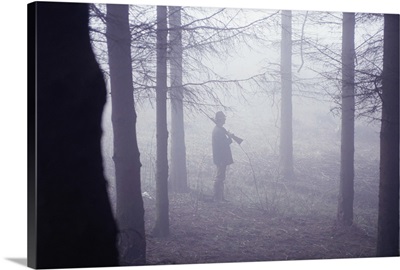Man with rifle in forest, side view