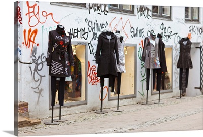 Manequins outside, facade covered in graffiti.