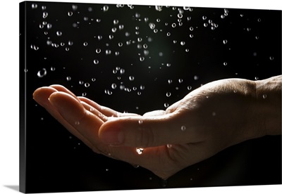 Man's hand catching falling rain drops