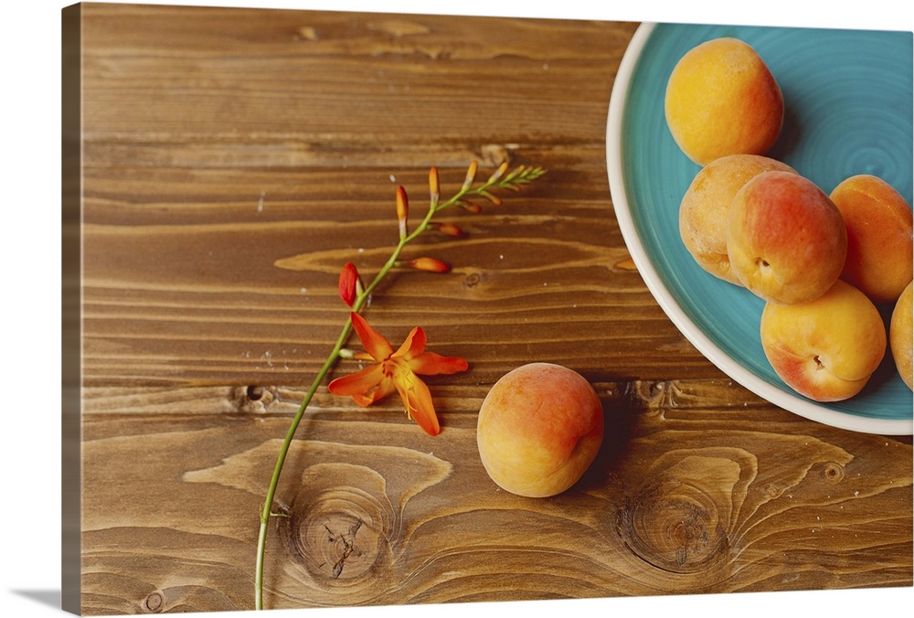 Several peaches amarillos with orange flower on rustic wooden table.