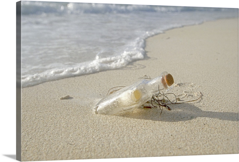 An old liquor bottle contains a note inside it's corked top sitting half sunken in the sand as waves lap against the shore.
