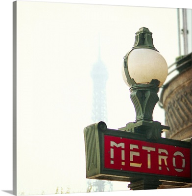 Metro sign in Paris with Eiffel Tower in the  background.
