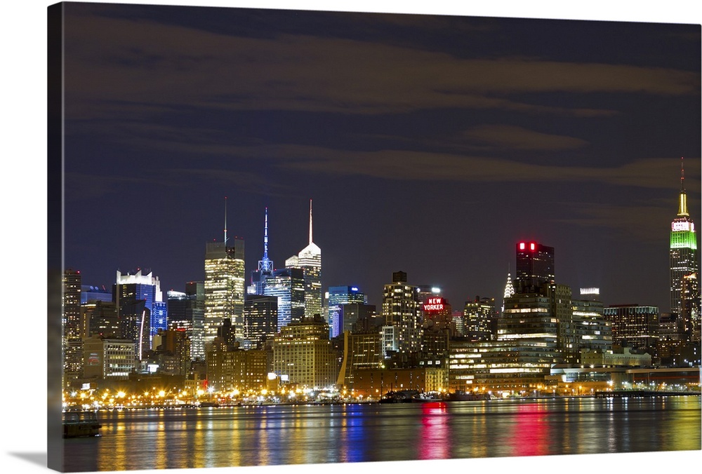 Giant landscape photograph of the brightly lit Manhattan skyline at night, reflecting in the water.