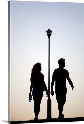 Middle aged man and woman walk past electricity lamp post