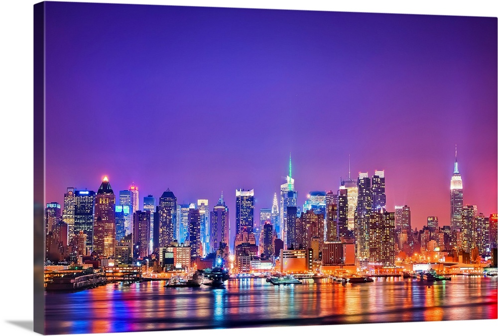 Photograph of New York skyline at night with the Hudson River in foreground.  The building lights are reflected in the water.