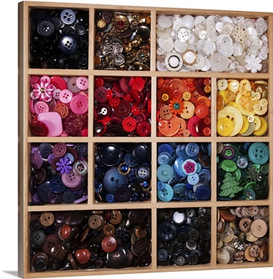 Modern and antique buttons sorted by color in divided wooden tray.