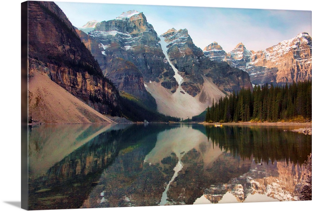 An early morning image of the beautiful Moraine Lake in Banff National Park Alberta Canada. A lone kayak makes its way acr...